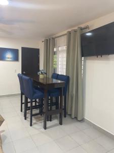 uma sala de jantar com uma mesa de madeira e cadeiras azuis em Departamento gaviota em Cozumel