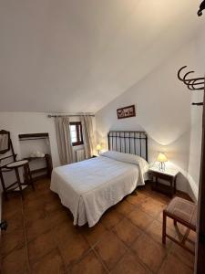 a bedroom with a large white bed and a table at Casa Rural Cortijo El Helao in Pozo Alcón