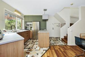 a kitchen with green cabinets and a staircase at Carlton Dream: Leafy 2bed 2bath Lygon Str Townhouse in Melbourne