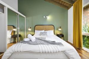 Carlton Dream: Leafy 2bed 2bath Lygon Str Townhouse في ملبورن: سرير أبيض كبير في غرفة بجدران خضراء