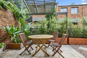 una mesa de madera y sillas en un patio en Carlton Dream: Leafy 2bed 2bath Lygon Str Townhouse en Melbourne