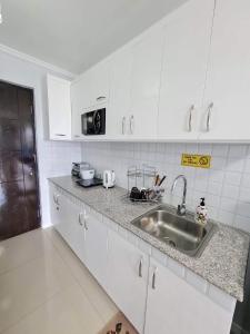 a kitchen with white cabinets and a stainless steel sink at Spacious 2-bedroom condo,Wifi,Netflix,Parking,Pool in Cagayan de Oro