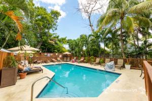 a swimming pool with a person laying on a chair next to it at The Island Suite at KW Vacation in Key West