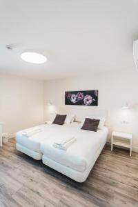 Cama blanca grande en habitación con suelo de madera en Hostal Comfort Suites, en Carrión de los Condes