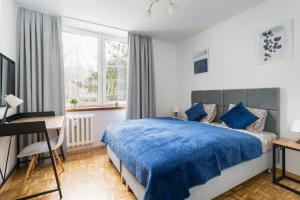um quarto com uma cama azul e uma secretária em Verdant Sadyba em Varsóvia