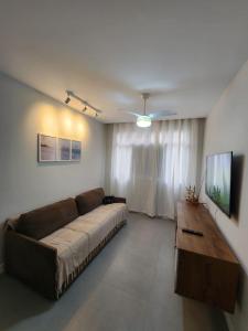 sala de estar con sofá grande y TV en Quadra do mar de Jardim Camburi, en Vitória