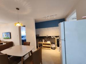 a kitchen and dining room with a table and a refrigerator at Quadra do mar de Jardim Camburi in Vitória