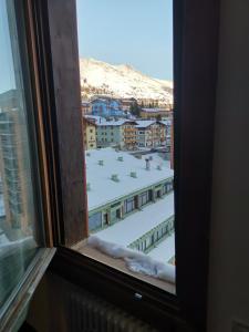 a window with a view of a snow covered city at Soleneve in Passo del Tonale
