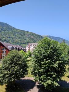 twee bomen voor een gebouw met een berg bij T3 cosy au Jardin du Ramel in Luchon