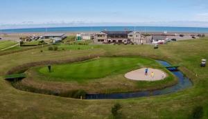 a man is standing on a golf course at Harbour View Apartment in Llandrillo-yn-Rhôs