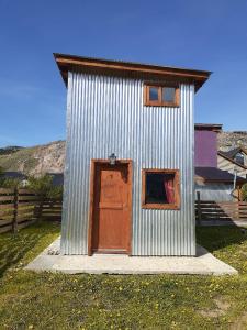 a small metal building with a door and two windows at Cerro Rosado in El Chalten