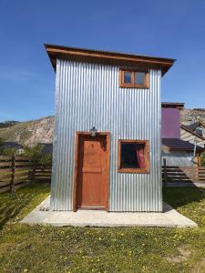 un pequeño edificio de metal con una puerta y dos ventanas en Cerro Rosado en El Chaltén