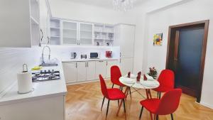 a white kitchen with red chairs and a table at Spacious 5* luxury in historic center free parking in Cluj-Napoca