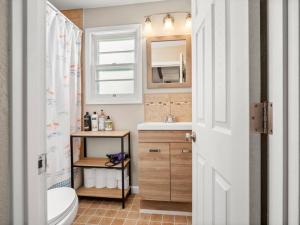 a bathroom with a sink and a toilet and a window at Adorable Wawasee Cottage in Oakwood Park in Syracuse +48 photos