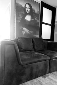 a black couch in a living room with a picture of a woman at Gioconda’s Apartment in Rome