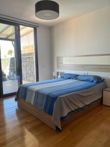 een slaapkamer met een bed met een blauw dekbed bij Villa Jaira in La Vegueta