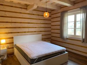 a bedroom with a bed in a room with wooden walls at Roubenka ARCHA in Dolní Morava