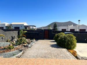 un jardín con una pasarela de ladrillo y una valla en Villa Jaira, en La Vegueta