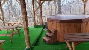a wooden igloo with a bench and a green floor at Brancoveanu Glamping in Văratici
