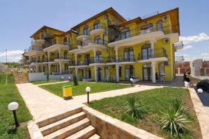 a large yellow building with stairs in front of it at Menada Green Hills Apartments in Sozopol