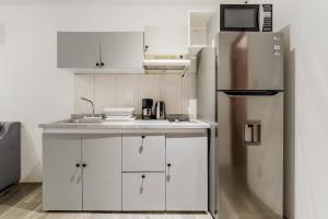 a kitchen with white cabinets and a stainless steel refrigerator at HotelZone L20 Beach Access in Cancún