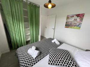 a bedroom with a black and white bed with green curtains at La villa Jalna Grenadine deux chambres et piscine privée in Les Trois-Îlets