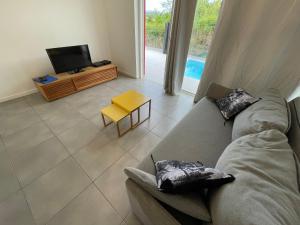 a living room with a couch and a tv at La villa Jalna Grenadine deux chambres et piscine privée in Les Trois-Îlets
