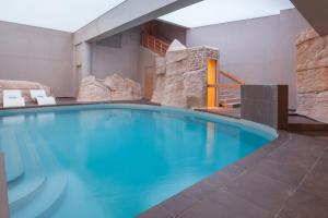 a large swimming pool with blue water in a building at Royal Ours Blanc Boutique Hôtel & Spa in L'Alpe-d'Huez