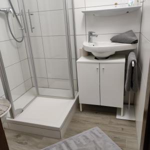 a white bathroom with a shower and a sink at Hotel - Landgasthof Post in Bichlbach