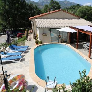 einen Pool vor einem Haus mit Stühlen und einem Sonnenschirm in der Unterkunft Maison Castellane Chambre d'Hotes B&B in Castellane