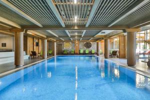 a large swimming pool with blue water in a building at Pirin Golf Private Apartments & Studios in Razlog