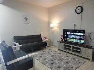 Una sala de estar con un sofá y un televisor de pantalla plana. en VIRTA Guesthouse, en Sandakan