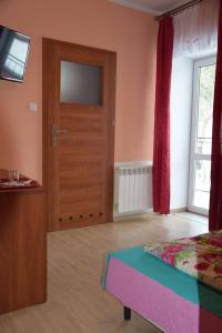 シュチトナにあるOśrodek Wypoczynkowy Pod Skałkąのベッドルーム(ベッド1台、テレビ、ドア付)