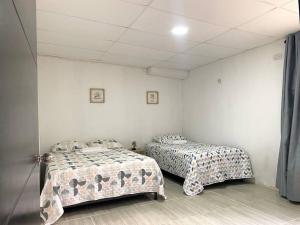 two beds in a room with white walls at Apto #6 hermoso y amplio in Ríohacha