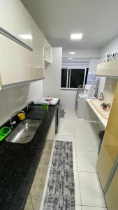 uma cozinha com um lavatório e uma bancada preta em Beach thoow férias em Arraial do Cabo