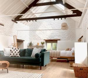 uma sala de estar com um sofá verde e uma cama em Beautiful self-contained Cotswolds Barn em Yatton Keynell