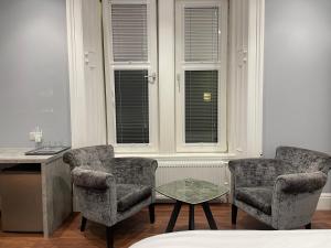 two chairs and a table in a room with windows at Laurieston Inn 