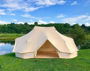 a large tent sitting in the grass next to a pond at Huntley lodge pp in Liverpool