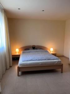a bedroom with a bed and two lamps on tables at Beautiful house with free parking on premise in Utzenstorf
