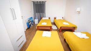 4 Betten in einem Zimmer mit gelber Bettwäsche in der Unterkunft Apartment miTski Kop in Kopaonik