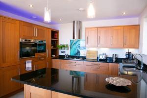 a kitchen with wooden cabinets and a black counter top at Wow I'm living on the beach. Luxury 4 bed sleeps 8 in Pagham