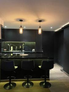 una cocina con encimera negra con sillas. en Black Loft. Moderno y nuevo, súper ubicado., en Ciudad de México