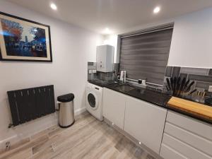a kitchen with a sink and a washing machine at Luton Town Centre Executive Apartment in Luton