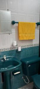 un bagno con lavandino verde e asciugamano giallo di Helena Hostel a Cali