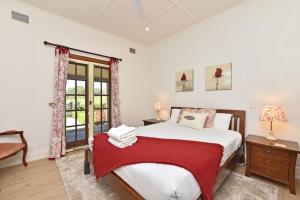 Un dormitorio con una cama grande y una ventana en Brokenback Vineyard Cottage, en Pokolbin