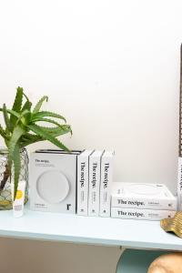 a stack of books on a shelf with a plant at The Oyster Inn in Oneroa