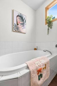 a white bathroom with a bath tub and a towel at Two houses from the beach 100m to Sand and Surf Sea Views in Torquay
