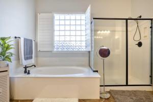 a white bathroom with a tub and a window at Modern Paradise: King Bed + EV Charger +Pool Table in Goodyear