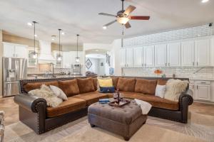 a living room with a brown couch and a ceiling fan at Modern Paradise: King Bed + EV Charger +Pool Table in Goodyear