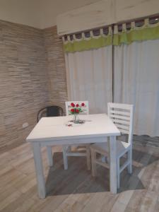 a white table with two chairs and a vase of flowers on it at Monoambientes in Villa Alsina